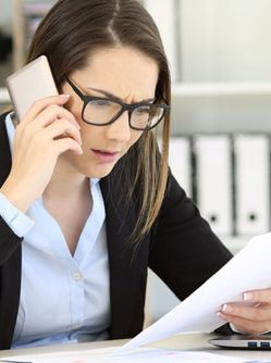 Une femme au visage inquiète est au téléphone et tient un document dans l'autre main - MACSF